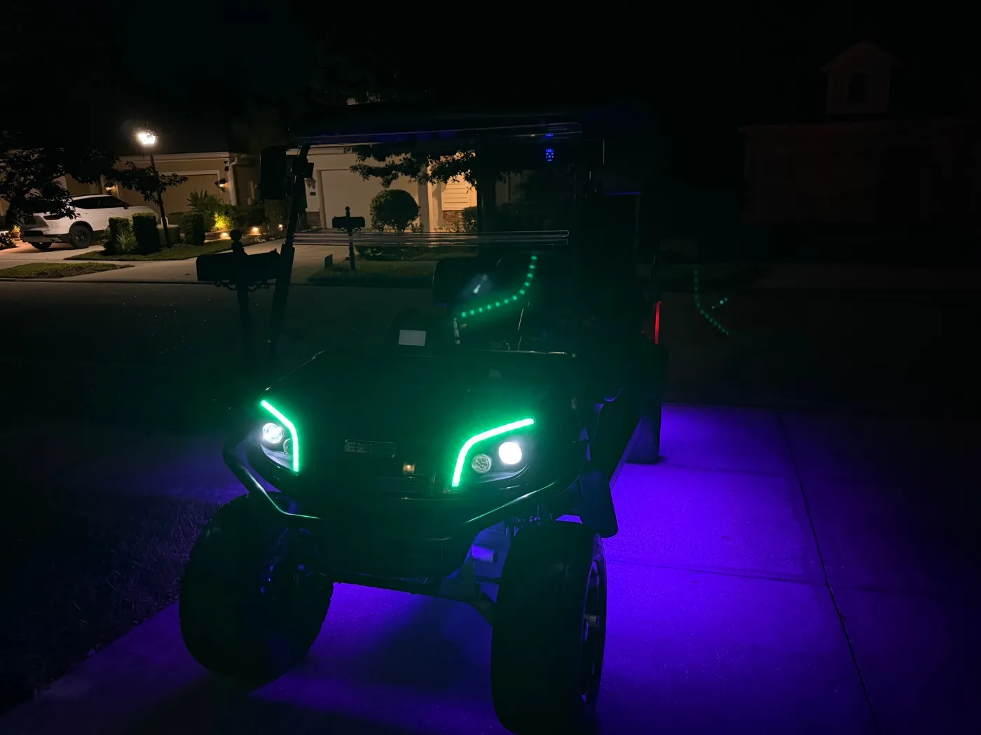 A lifted black six-seat golf cart at night with green headlight halos and purple underglow