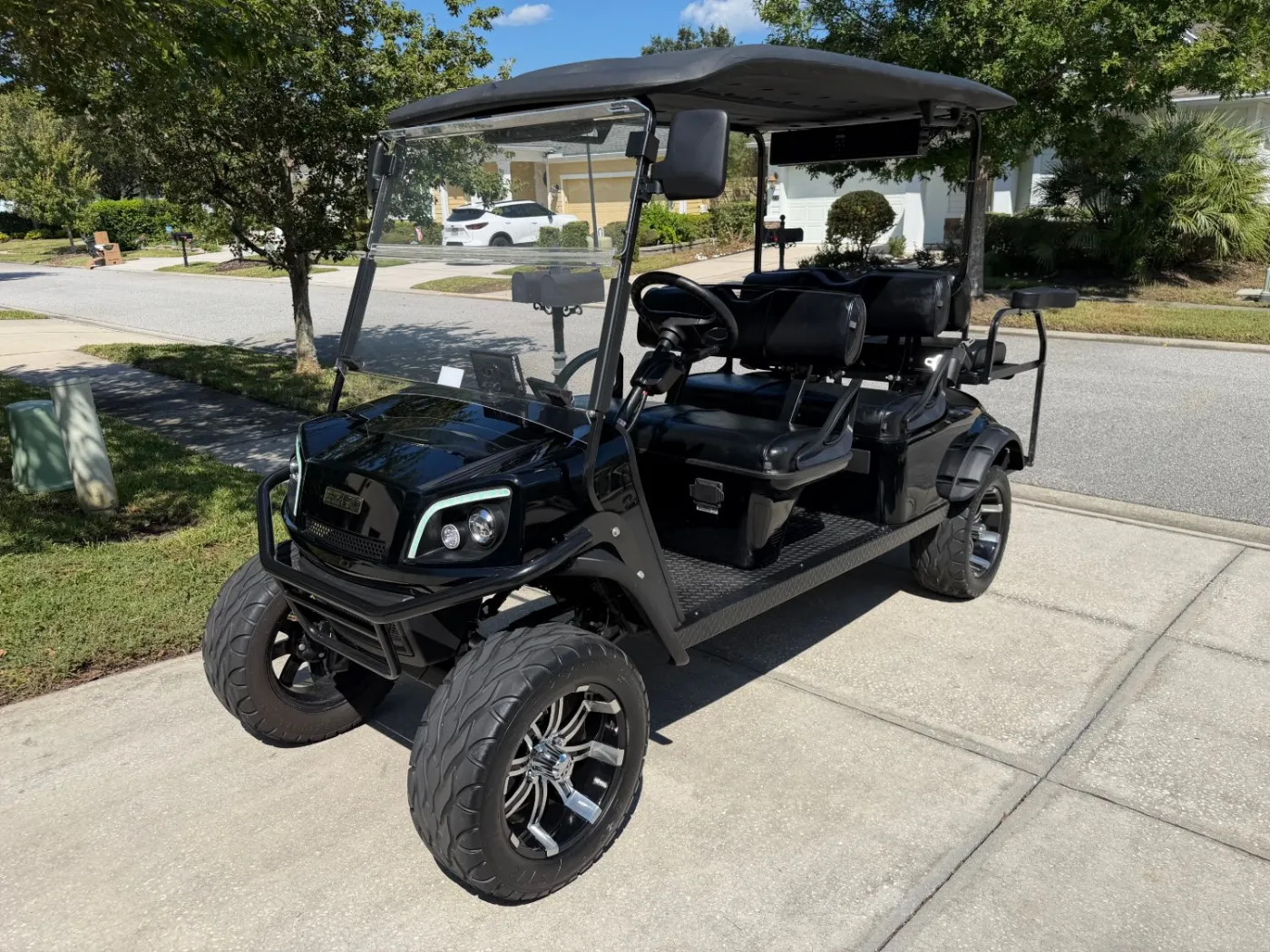 Lifted black six-seat cart on a driveway